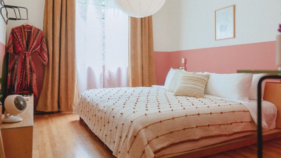 coral and white walls with double bed with handwoven throw and robe in guestroom at hotel San Fernando by bunkhouse