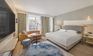 grey walls, blue carpet and white linen on the bed in the guestroom at Hyatt Regency London Blackfriars