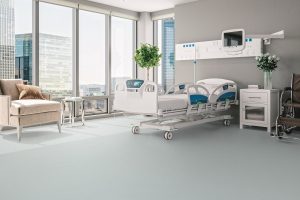 hospital room with bed and chair in front of floor to ceiling windows looking ocer the city and grey safety flooring