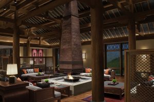 lounge with central fireplace surrounded by seating and columns and panels in traditional tibetan designs