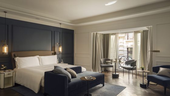 guestroom in Intercontinental Rome with dark grey wall behind the bed, white linen and grey and wood surfaces with seating in window area
