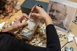 mosaic artist working on a portrait in mosaic tiles on a bottle
