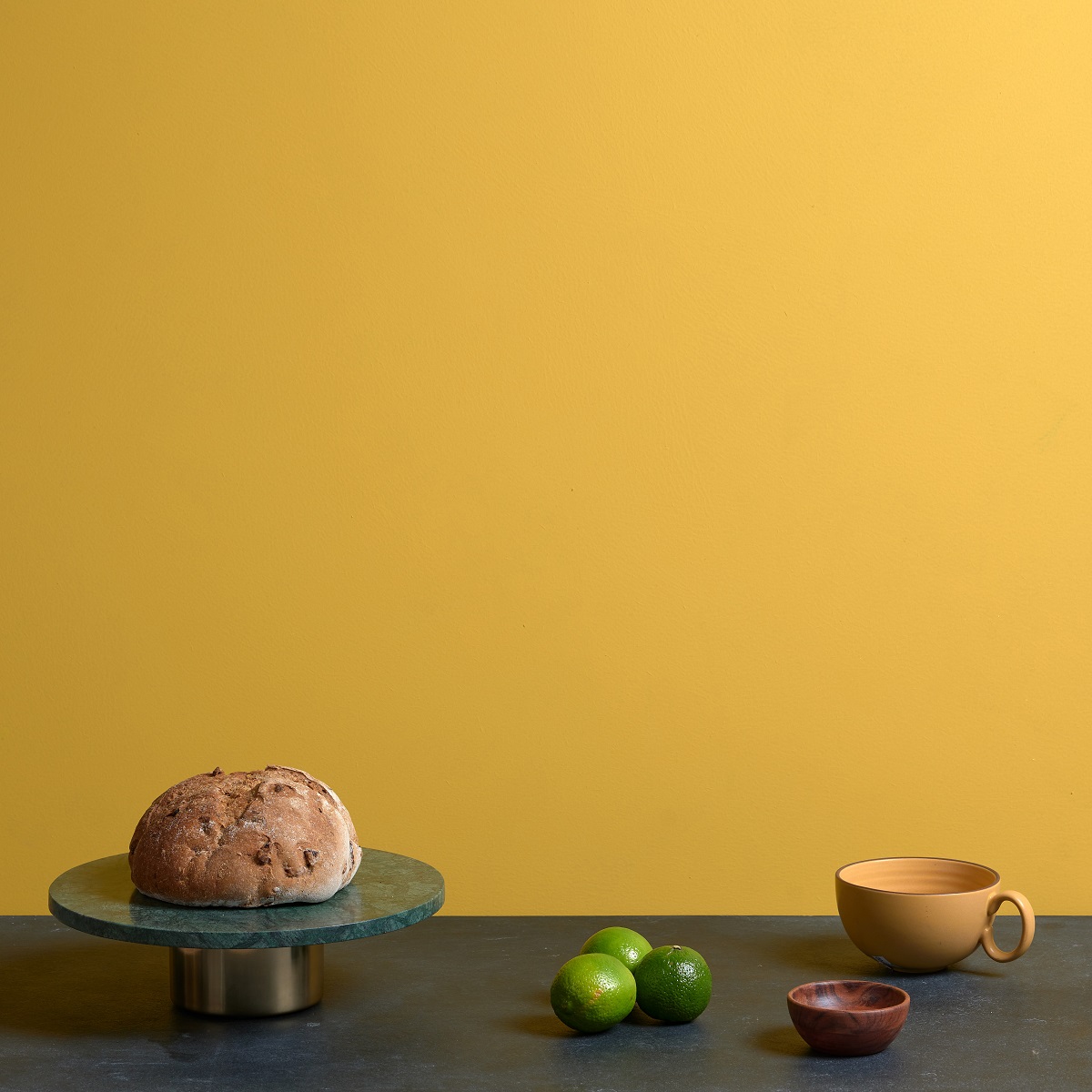still life of bread and cup on a table with wall behind painted in Ottos Gold from hyperion tiles