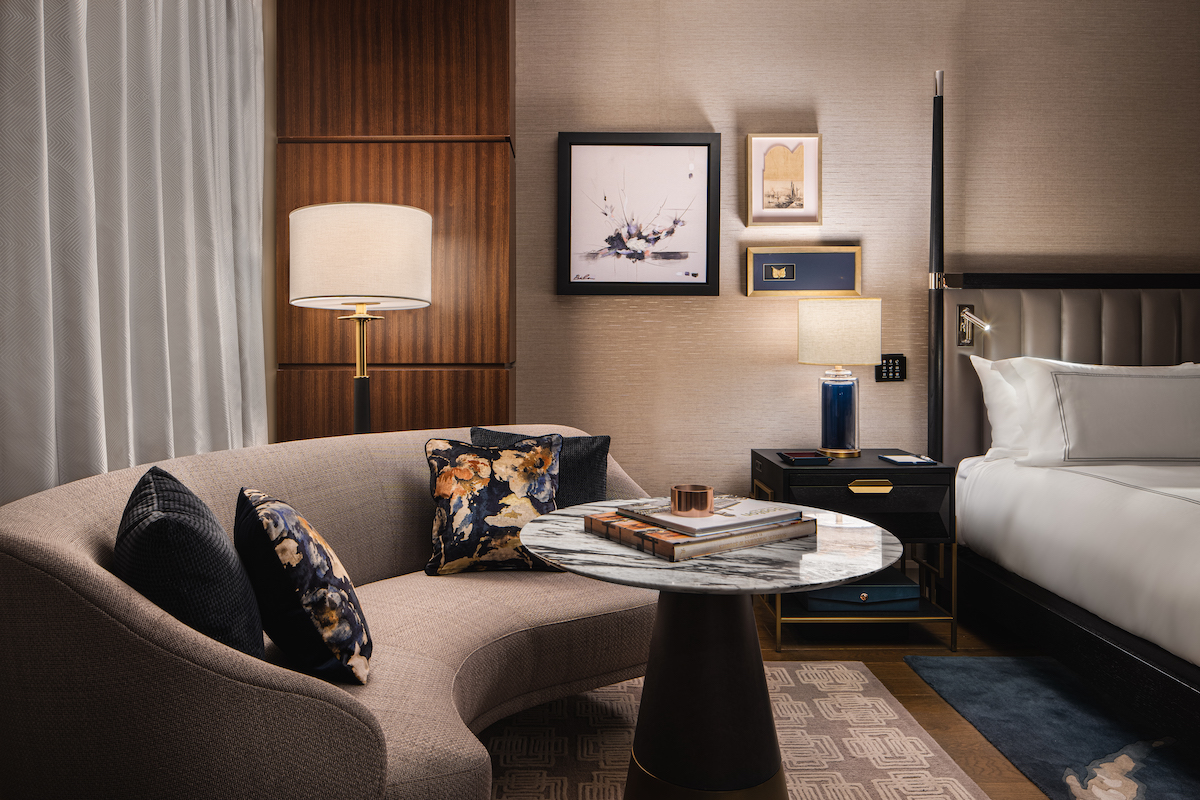 A render of a luxury bedroom in a hotel in Boston with blue carpets and dark wood finishes