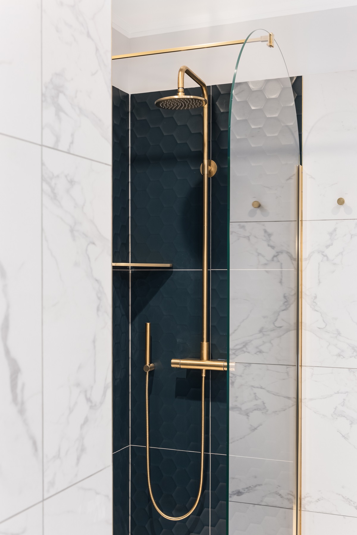arch shaped glass shower screen in apartment in Rome with black and marble tiles and gold fittings