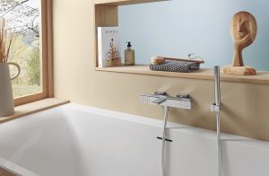 chrome tap over bath alongside wooden insert shelf with wooden sculpture and accessories