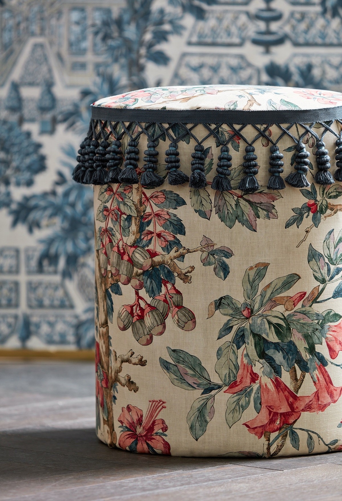 detail of footstool covered in floral zoffany fabric from arcadian thames collection with fringe detail and pattern wallpaper in background