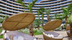 round wicker pool chairs with parasol in foreground with architectural detail of Waldorf Astoria Lusail in the background