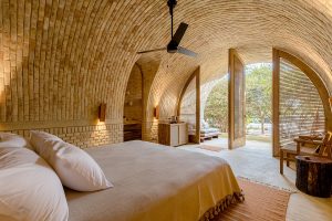 vaulted brick structure of guestroom with doors opening onto terrace and garden and interior in natural tones and textures