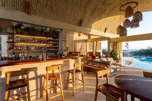 wooden bar stools at brick bar under vaulted ceiling overlooking the pool