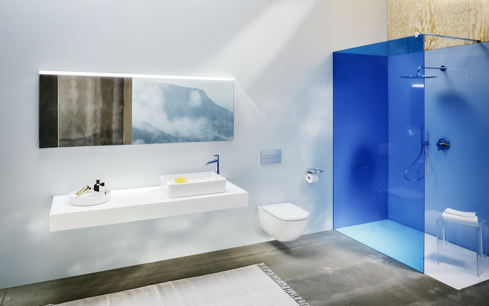 bathroom design with blue glass shower enclosure and white shower tray from Laufen next to double sink on a vanity below a mirror