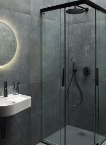 grey tiled bathroom with small black framed shower enclosure and black fittings