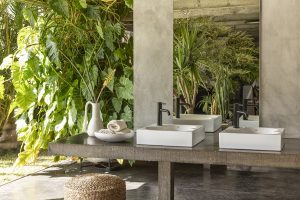 outdoor bathroom with concrete surfaces and tropical plants with white Roca Ohtake basin and black tap