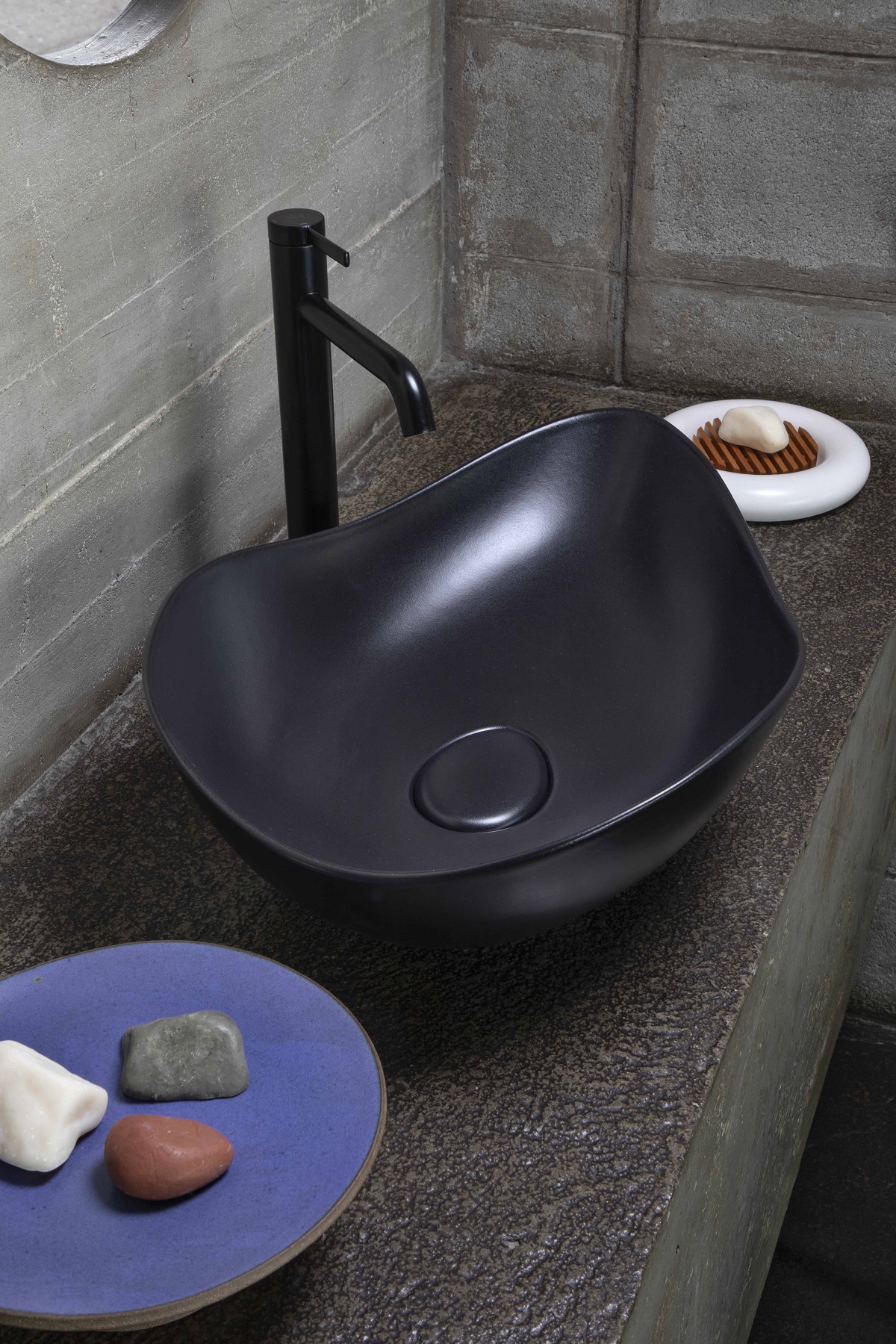 matt black curved counter top basin with black taps and concrete surface