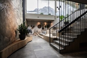textured concrete wall, window with mountain view and stone floor with architectural staircase