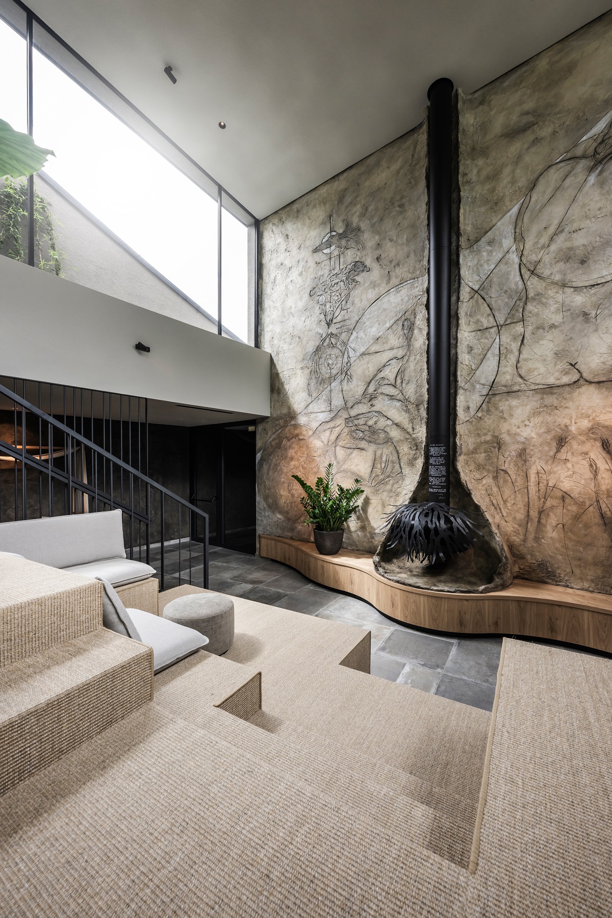 textured concrete backwall behind suspended fireplace in stepped central seating area