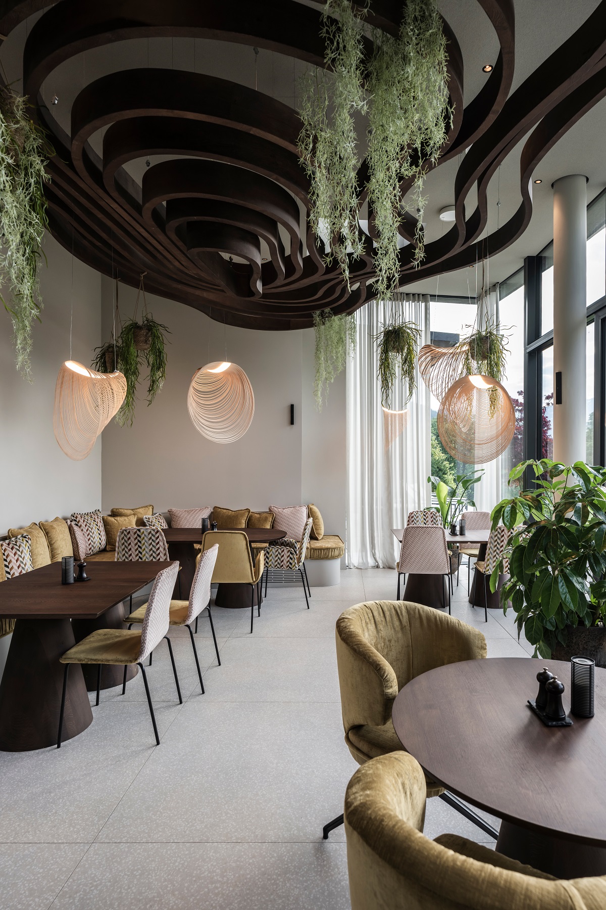 curved ceiling installation with plants above restaurant tables and seating in Puradies by NOA