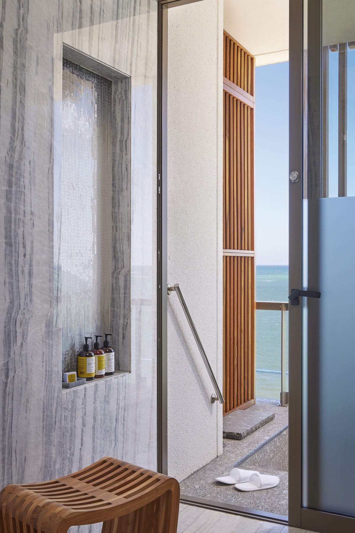 wooden stool in the indoor outdoor shower with door onto terrace in hotel guestroom