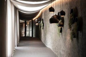 atmospheric corridor with natural textured walls, draped ceiling to filter light and woven pendant focus lighting
