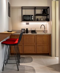kitchen dining area in compact aparthotel with red and black bar stools and a wood and black kitchen design