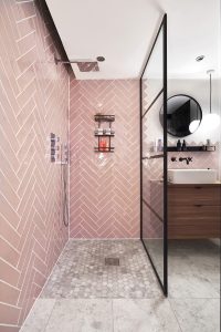 pink wall tiles in hexagonal pattern on the wall of shower enclosure with black fittings and marble tile detail on the shower floor