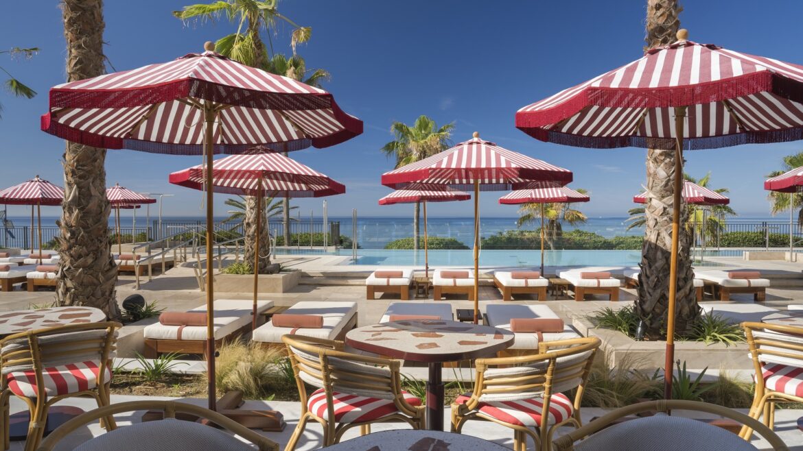 red and white striped umbrellas above tables and sunloungers around the pool at El fuerte marbella