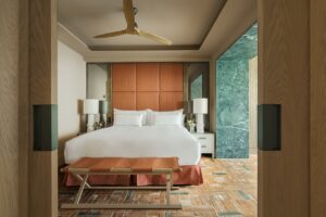 hotel guestroom with green wall and terracotta floor with wooden ceiling fan and surfaces