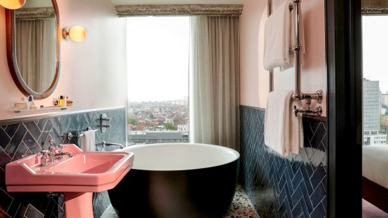 vintage pink basin in hotel bathroom with contemporary freestanding bath and blue wall tiles
