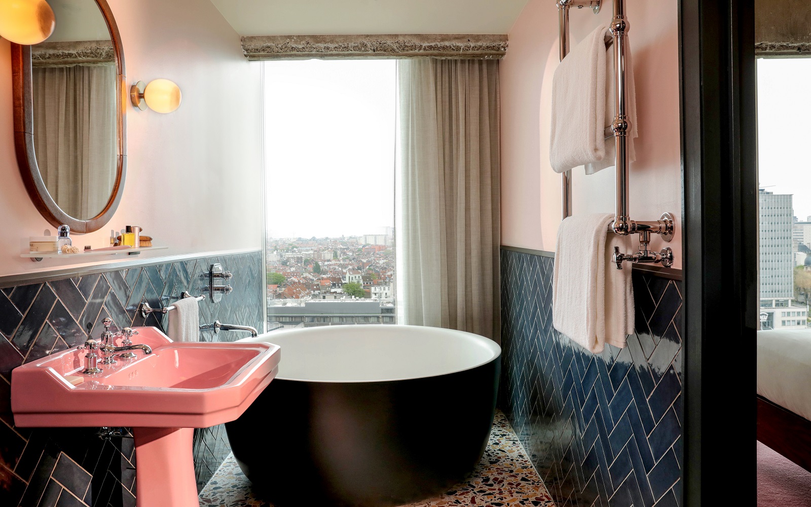 vintage pink basin in hotel bathroom with contemporary freestanding bath and blue wall tiles
