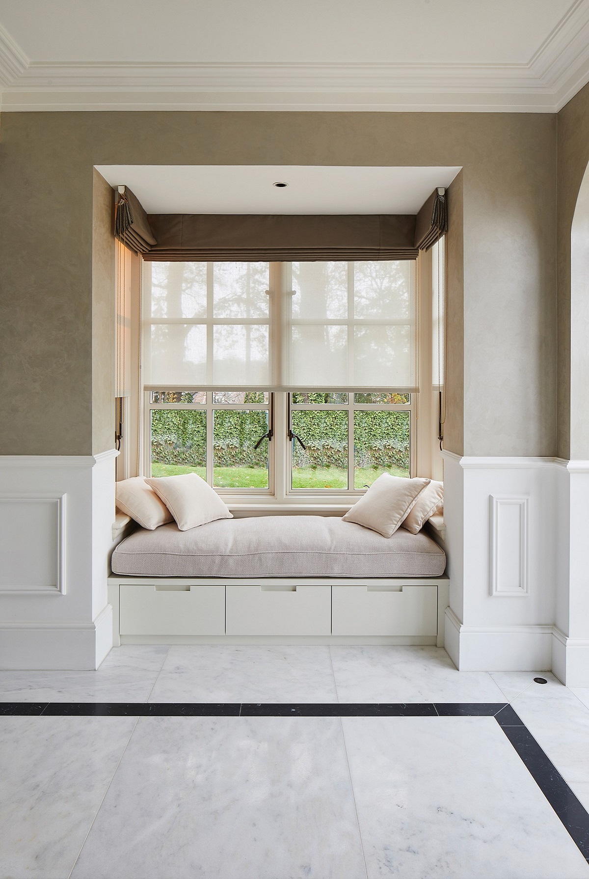 window seat in square window frame with white and grey tiled marble floor