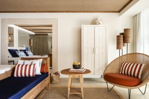 blue couch with brown and white striped cushion, wooden furniture and wicker chair in the guestroom at Melia Zel Palmanova Mallorca