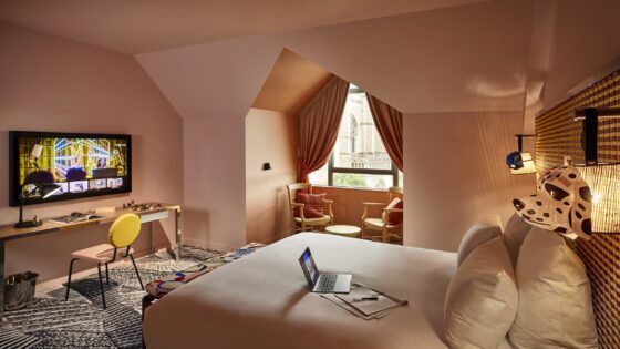 guestroom in Mama Shelter Dijon with walls in shades of terracotta pink and patterned carpets with comic strip lighting