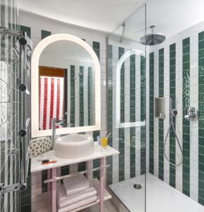 striped vertical tiling on the bathroom wall with arched mirror above Tom Dixon basin