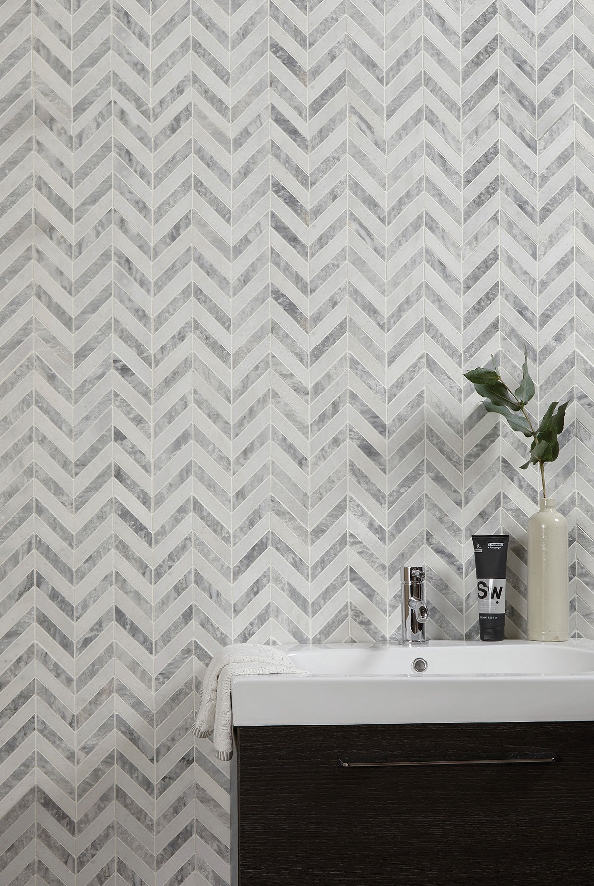 bathroom vanity with small chevron marble tile design behind on the wall