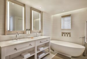 hotel bathroom with white freestanding bath, double vanity and mirrors in wood frame
