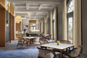 blue carpet, tables and seating, arched windows and a coffered ceiling in the hotel club lounge