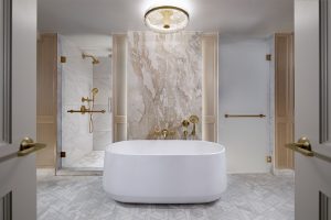 white free standing bath in a suite with grey and brown marble and gold finishes