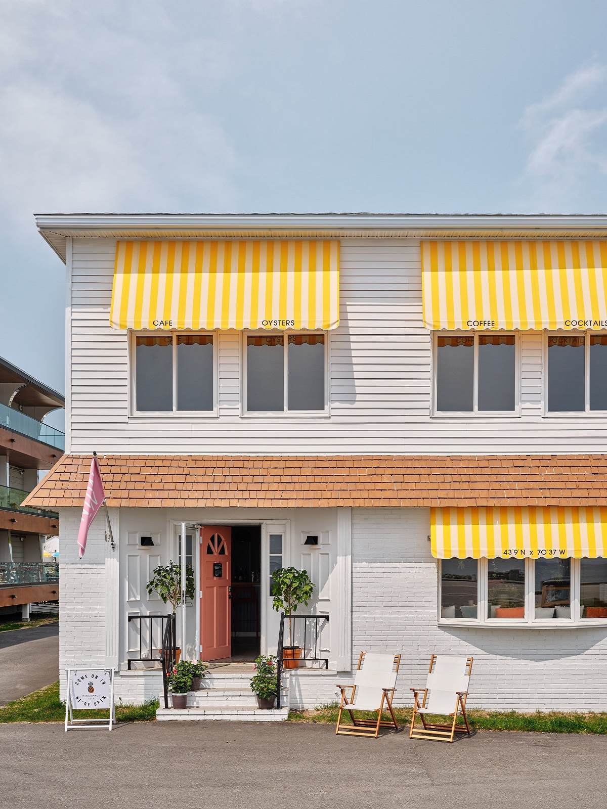 exterior motel style vintage hotel facade with yellow striped awnings and clapboard surface details