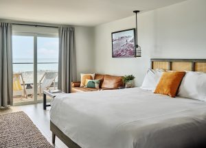 guestroom with views onto the beach and the surf with white linen and a leather couch