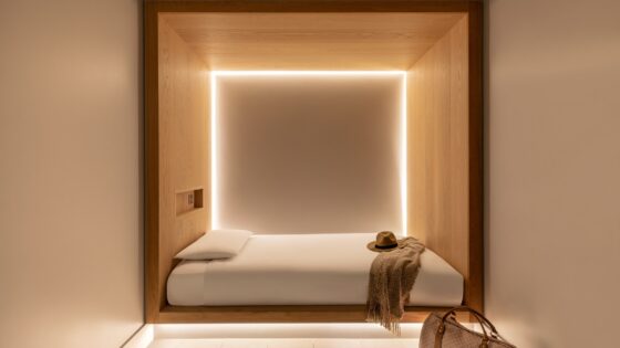 cocoon like hotel guestroom with bed at the end with lighting integrated on wall and no windows