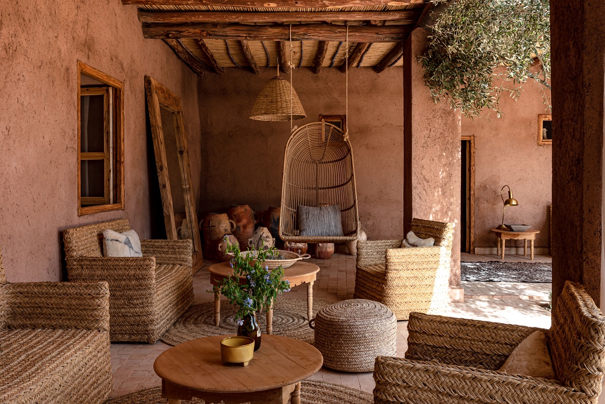 outdoor seating area with red clay walls and woven rush furniture with wooden tables in Marrakech