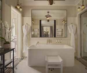 square freestanding bath in front of large square mirror with tiled floor and period details