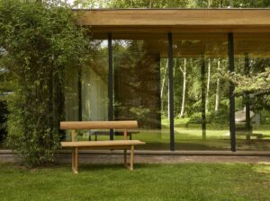 outdoor wooden Banco Bench in garden in front of glass doors design by Fritz Hansen