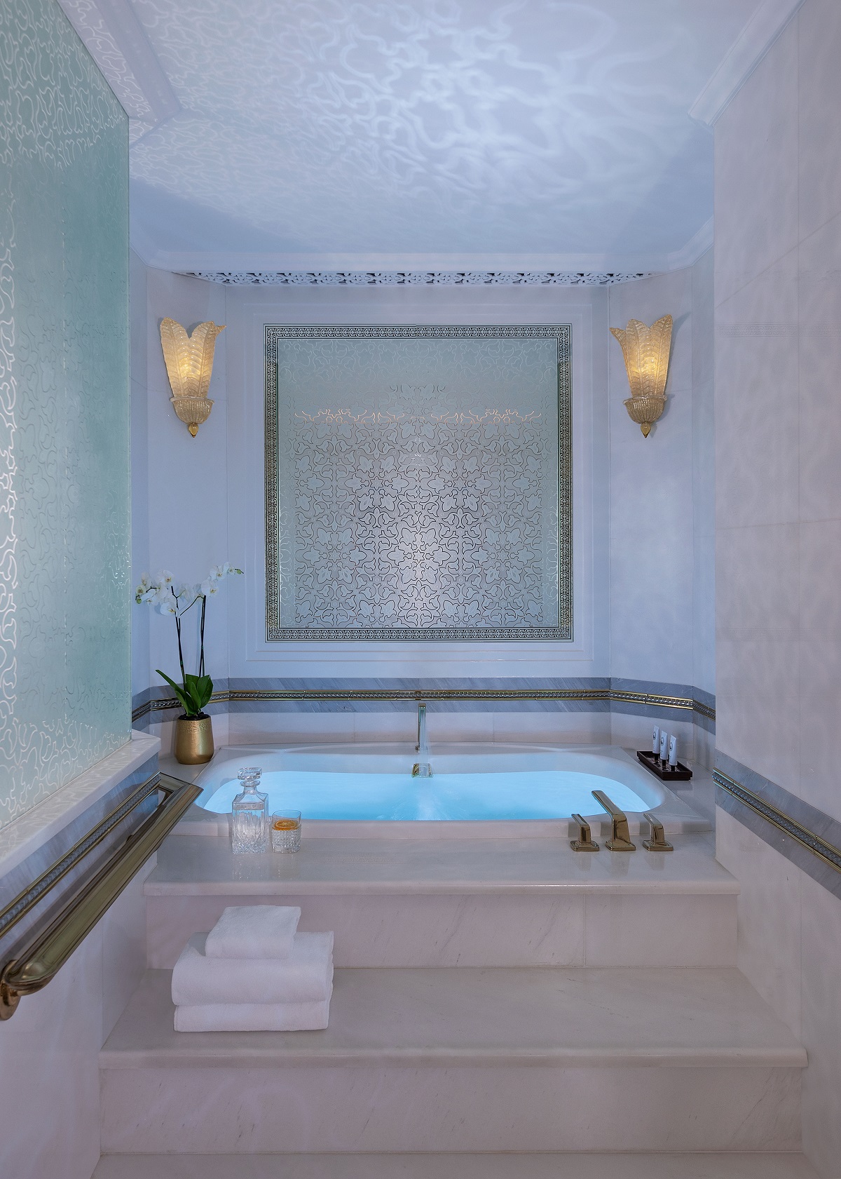 sunken bath in Mandarin Oriental Emirates with corner lighting and steps up to the bath in hammam style bathroom