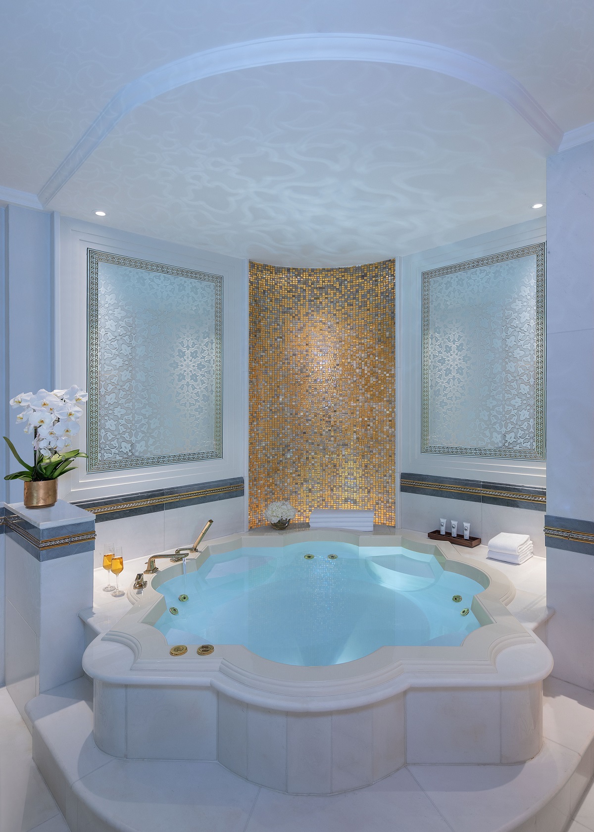 bathroom with gold mosaic tiles and lotus shaped spa style bath under domed ceiling