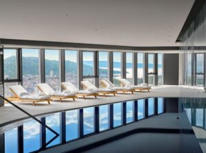 indoor swimming pool in AC Marriott Split with sun loungers set against floor to ceiling window looking out over the city