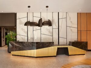 minimalist reception desk with marble panelling behind and statement lighting above in hotel lobby