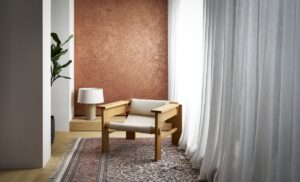 low wooden chair in front of brown patina wallcovering 
