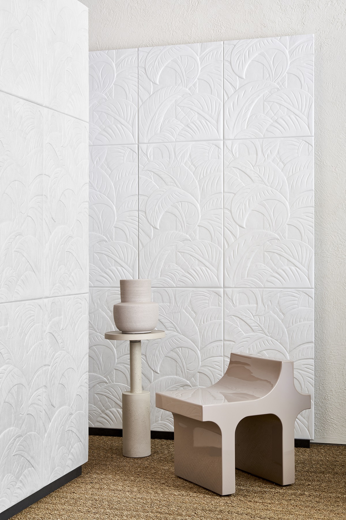 contemporary cream coloured chair and pot in front of white relief wallcovering covered with foliage