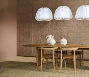 wooden table and chairs with white ceramic jugs on the table and white lantern lampshades in front of terracotta wallcovering in panels